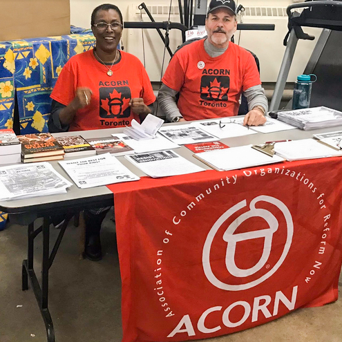 Bob Murphy sitting with an ACORN member at  an information table