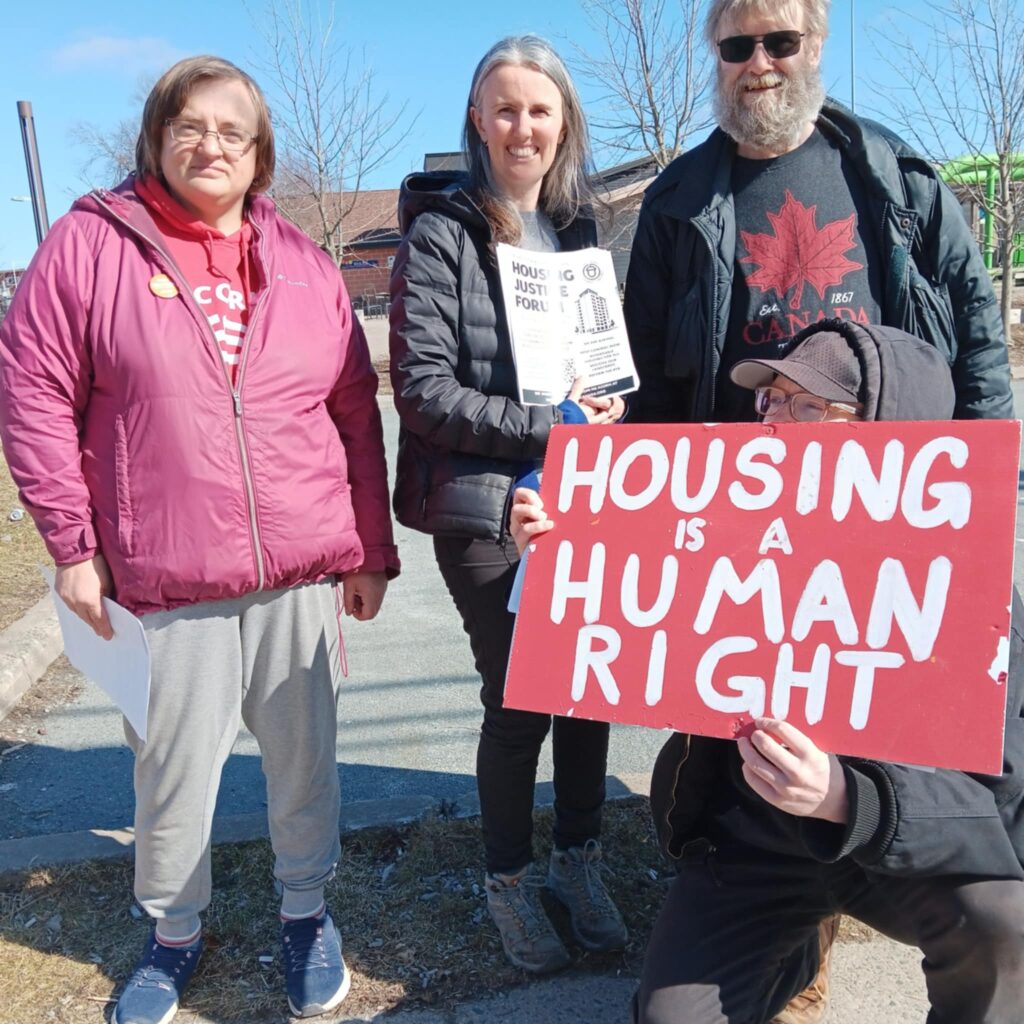 Halifax ACORN Dartmouth members on national day of action with flyers. Sign reads "Housing is a Human Right"