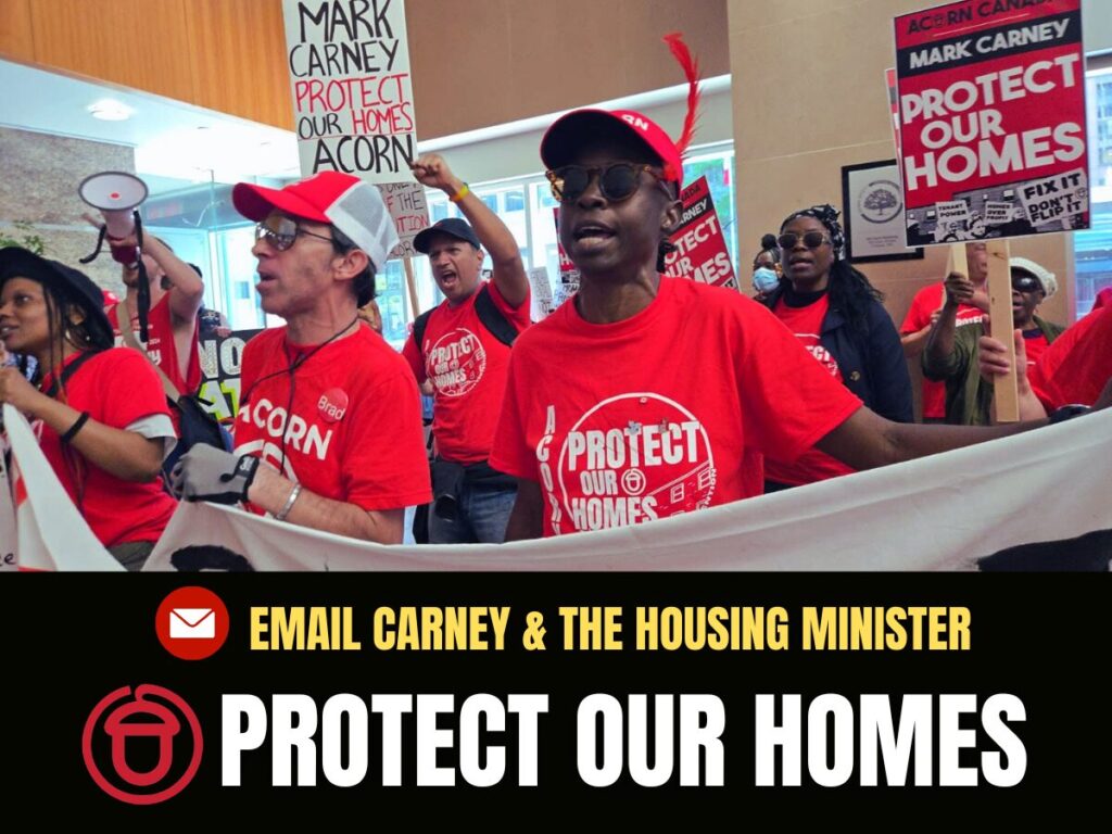 Protesters wearing red shirts hold signs reading ‘Protect Our Homes’ inside a building with a bold banner below.